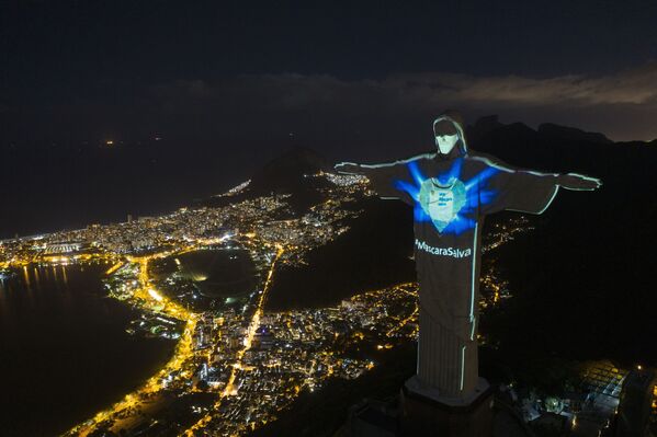 In this 3 May 2020 photo, the iconic Christ the Redeemer statue is lit up as if wearing a protective mask and features a hashtag that reads Mask saves in Portuguese, amid the new coronavirus pandemic in Rio de Janeiro, Brazil.  - Sputnik International