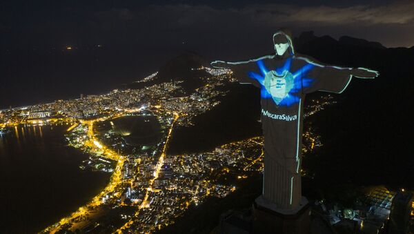 In this Sunday, May 3, 2020 photo, the iconic Christ the Redeemer statue is lit up as if wearing a protective mask and with a hashtag that reads in Portuguese: Mask saves, amid the new coronavirus pandemic, in Rio de Janeiro, Brazil.  - Sputnik International