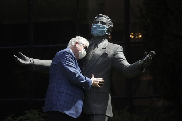 Paul Tormey, Regional Vice President of Fairmont Hotels, wears a mask while hugging a statue of singer Tony Bennett outside of the Fairmont San Francisco hotel before leading hotel workers in a singing of the song I Left My Heart in San Francisco, 25 April 2020, in San Francisco. - Sputnik International