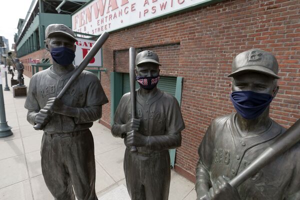 Statues of former Boston Red Sox greats, from left, Ted Williams, Bobby Doerr and Johnny Pesky, wear protective masks outside Fenway Park, 17 April 2020, in Boston.  - Sputnik International