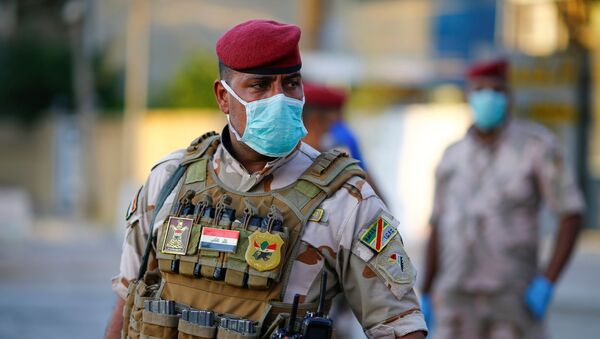 An Iraqi soldier wears a protective face mask as he stands guard at a check point, enforcing a curfew imposed to prevent the spread of the coronavirus disease (COVID-19), during the holy fasting month of Ramadan, in Baghdad, Iraq May 3, 2020 - Sputnik International