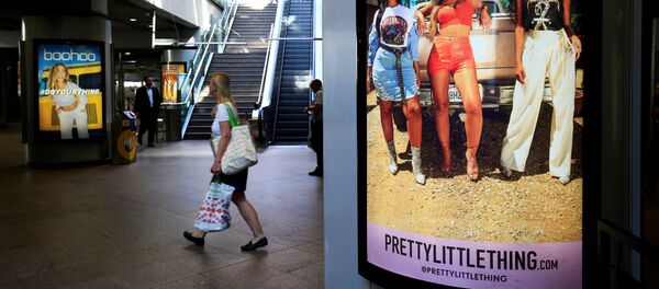 A shopper walks past an advertising billboards for Boohoo and for 'Pretty Little Things', a Boohoo brand, at Canary Wharf DLR station in central London, Britain, 17 September 2018 A shopper walks past an advertising billboards for Boohoo and for 'Pretty Little Things', a Boohoo brand, at Canary Wharf DLR station in central London, Britain, 17 September 2018 - Sputnik International