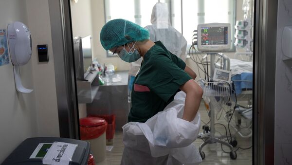 A nurse takes off her personal protective equipment (PPE) after treating a COVID-19 patient - Sputnik International