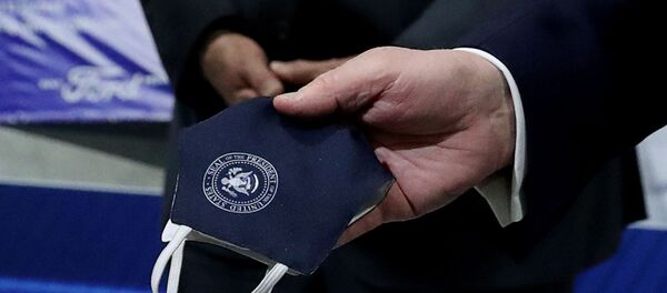 U.S. President Donald Trump holds a protective face mask with a presidential seal on it that he said he had been wearing earlier in his tour at the Ford Rawsonville Components Plant that is manufacturing ventilators, masks and other medical supplies during the coronavirus disease (COVID-19) pandemic in Ypsilanti, Michigan, U.S., May 21, 2020 - Sputnik International