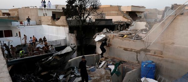 People stand on a roof of a house amidst debris of a passenger plane, crashed in a residential area near an airport in Karachi, Pakistan May 22, 2020. - Sputnik International