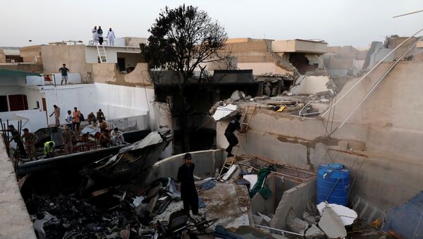 People stand on a roof of a house amidst debris of a passenger plane, crashed in a residential area near an airport in Karachi, Pakistan May 22, 2020. - Sputnik International