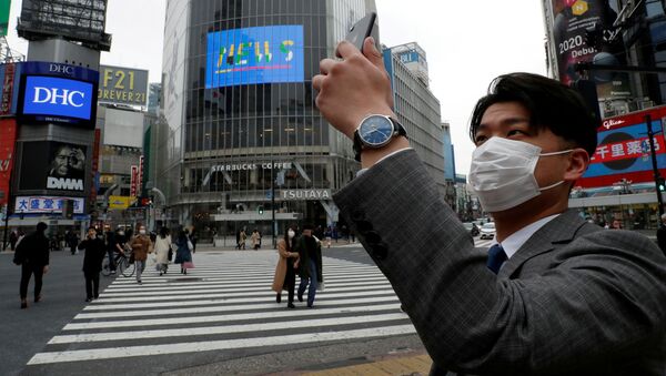 A man wearing a protective face mask, takes a photo with his mobile phone at noon, at Shibuya Crossing, during the coronavirus disease (COVID-19) outbreak, in Tokyo, Japan, March 31, 2020.  - Sputnik International