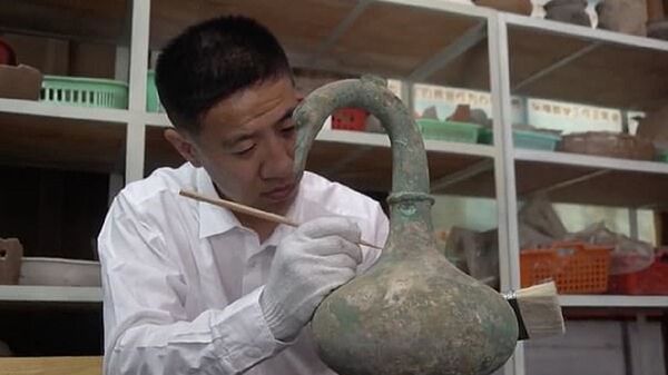 Researcher Yan Fei cleaning the swan-shaped Chinese ritual bronze unearthed in a tomb in Sanmenxia, Henan, China - Sputnik International
