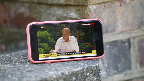 A mobile phone is seen resting on a wall outside the house of Dominic Cummings, special advisor for Britain's Prime Minister Boris Johnson, as it displays a live stream of a statement by Cummings following the outbreak of the coronavirus disease (COVID-19), London, Britain, May 25, 2020. - Sputnik International