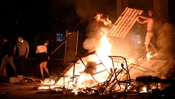 A protester adds wood to a fire barricade on 26th Ave S near the Minneapolis Police third precinct after a white police officer was caught on a bystander's video pressing his knee into the neck of African-American man George Floyd, who later died at a hospital, in Minneapolis, Minnesota, U.S. May 27, 2020. Picture taken May 27, 2020 - Sputnik International