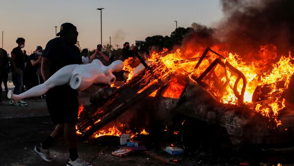 A man prepares to throw a mannequin onto a burning car at the parking lot of a Target store during protests after a white police officer was caught on a bystander's video pressing his knee into the neck of African-American man George Floyd, who later died at a hospital, in Minneapolis, Minnesota, U.S., May 28, 2020 - Sputnik International