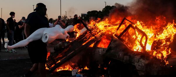 A man prepares to throw a mannequin onto a burning car at the parking lot of a Target store during protests after a white police officer was caught on a bystander's video pressing his knee into the neck of African-American man George Floyd, who later died at a hospital, in Minneapolis, Minnesota, U.S., May 28, 2020 - Sputnik International