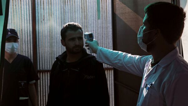 A Syrian man has his temperature checked at the entrance of a quarantine centre, where those entering from Turkey are carefully monitored as a preventive measure against the spread of the coronavirus disease (COVID-19), in the town of Jisr al-Shughour in Idlib province, Syria, 30 April 2020 - Sputnik International