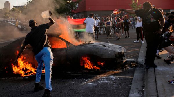 People react as a car burns at the parking lot of a Target store during protests after a white police officer was caught on a bystander's video pressing his knee into the neck of African-American man George Floyd, who later died at a hospital, in Minneapolis, Minnesota, U.S., May 28, 2020 - Sputnik International