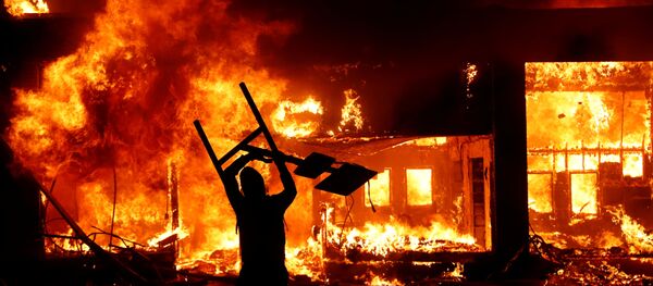 A protester holds an object in front of a fire during a demonstration against the death in Minneapolis police custody of African-American man George Floyd, in Minneapolis, Minnesota, U.S., early May 30, 2020.  - Sputnik International