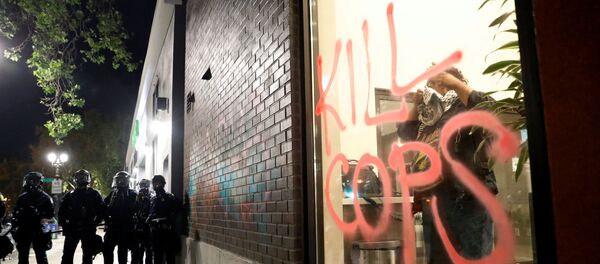 Police officers in riot gear stand guard during a protest against the death of African-American man George Floyd under Minneapolis police custody, in Oakland, California Police officers in riot gear stand guard during a protest against the death of African-American man George Floyd under Minneapolis police custody, in Oakland, California - Sputnik International