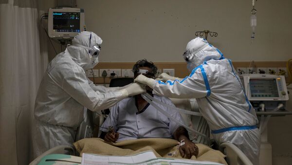 Medical workers wearing PPE take care of a patient suffering from COVID-19, at a hospital in New Delhi - Sputnik International