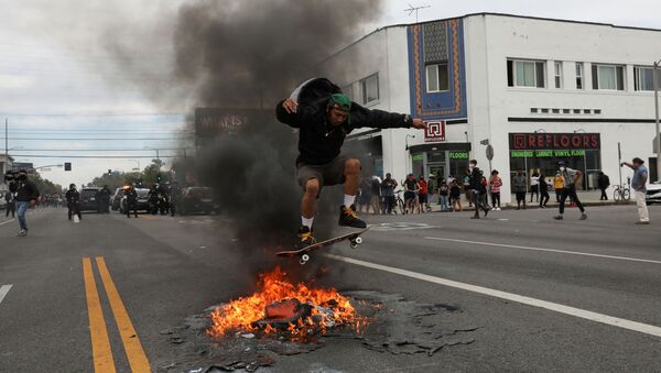 A man jumps with a skateboard over fire during a protest against the death in Minneapolis police custody of George Floyd, in Los Angeles, California, U.S., May 30, 2020. - Sputnik International