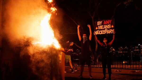 Demonstrators gesture and hold a sign next to a fire during a rally near the White House against the death in Minneapolis police custody of George Floyd in Washington, D.C. U.S. May 30, 2020.  - Sputnik International