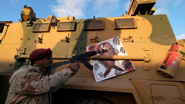 A member of Libyan National Army (LNA) commanded by Khalifa Haftar, points his gun to the image of Turkish President Tayyip Erdogan hanged on a Turkish military armored vehicle, which LNA said they confiscated during Tripoli clashes, in Benghazi, Libya January 28, 2020 - Sputnik International