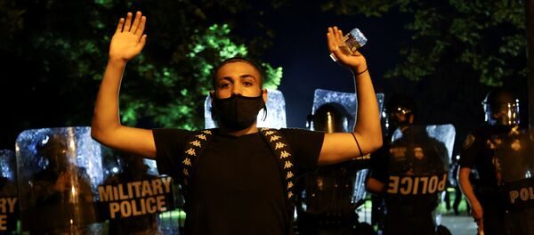 A demonstrator raises his hands as police officers and Washington, DC National Guard military police officers stand guard during a protest against the death in Minneapolis police custody of George Floyd, near the White House, in Washington, U.S., May 30, 2020 - Sputnik International