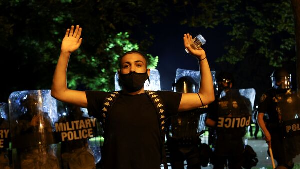 A demonstrator raises his hands as police officers and Washington, DC National Guard military police officers stand guard during a protest against the death in Minneapolis police custody of George Floyd, near the White House, in Washington, U.S., May 30, 2020 - Sputnik International