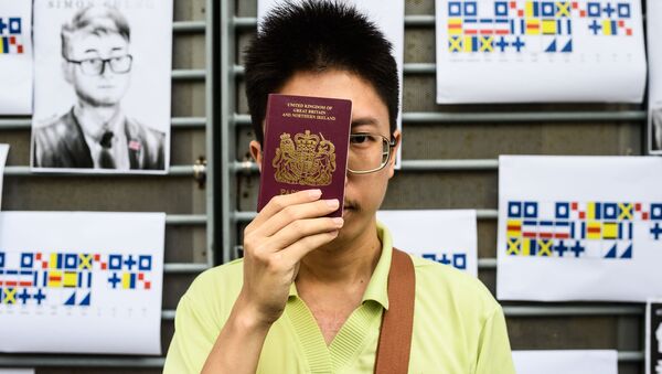 An activist holds a British passport while standing in front of placards carrying a message using International Code of Signals (ICS) flags, during a gathering outside the British Consulate-General building in Hong Kong on August 21, 2019 - Sputnik International