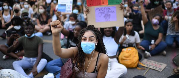 Demonstrators sit in the road near the US Embassy in London on May 31, 2020 to protest the death of George Floyd, an unarmed black man who died after a police officer knelt on his neck for nearly nine minutes during an arrest in Minneapolis, USA - Sputnik International