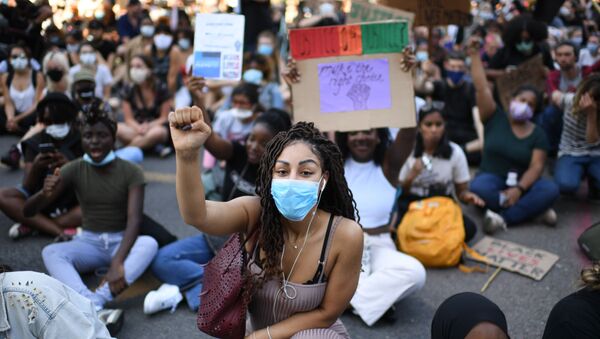 Demonstrators sit in the road near the US Embassy in London on May 31, 2020 to protest the death of George Floyd, an unarmed black man who died after a police officer knelt on his neck for nearly nine minutes during an arrest in Minneapolis, USA - Sputnik International
