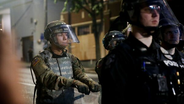 A member of the National Guard leans on his shield behind a line of Seattle police as protesters rally against police brutality and the death in Minneapolis police custody of George Floyd, near the police department's East Precinct location in Seattle, Washington, U.S. June 2, 2020. Picture taken June 2, 2020 - Sputnik International