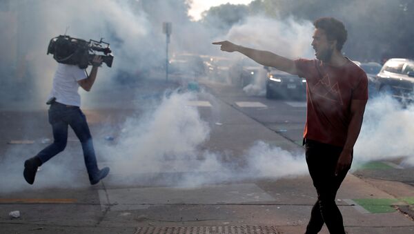 A protester argues with law enforcement officers as a reporter runs away from tear gas  - Sputnik International
