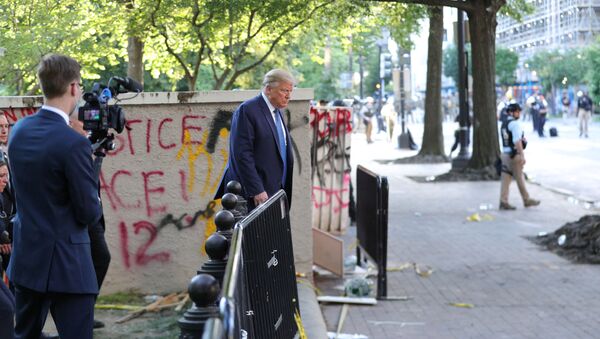 A White House videographer films U.S. President Donald Trump as he walks past a building defaced with graffiti by protestors in Lafayette Park across from the White House after walking to St John's Church for a photo opportunity during ongoing protests over racial inequality in the wake of the death of George Floyd while in Minneapolis police custody, outside the White House in Washington, U.S., June 1, 2020 - Sputnik International