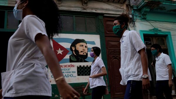 Medical students walk past an image of late Cuban President Fidel Castro as they check door to door for people with symptoms amid concerns about the spread of the coronavirus disease (COVID-19), in downtown Havana, Cuba, May 12, 2020. - Sputnik International