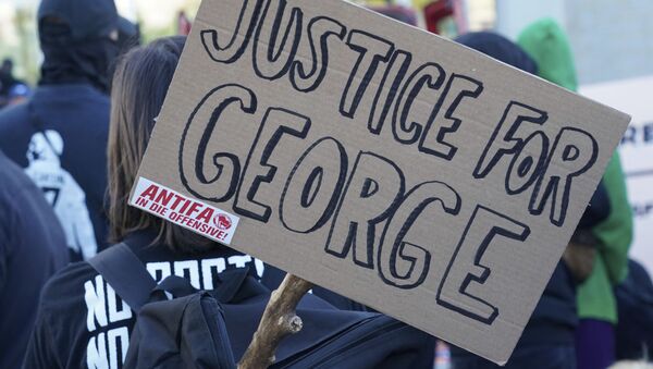 A poster with the inscription 'Justice for George' and 'Antifa on the offensive' is held by a protestor during a demonstration under the motto Youth Day - Fight for your future - Sputnik International