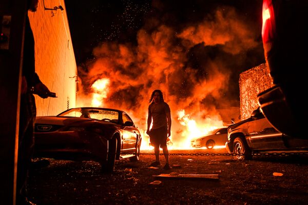 A man tries to toe away a car in a safe zone as the other car catches fire in a local parking garage on May 29, 2020 in Minneapolis, Minnesota, during a protest over the death of George Floyd, an unarmed black man, who died after a police officer kneeled on his neck for several minutes. - Sputnik International