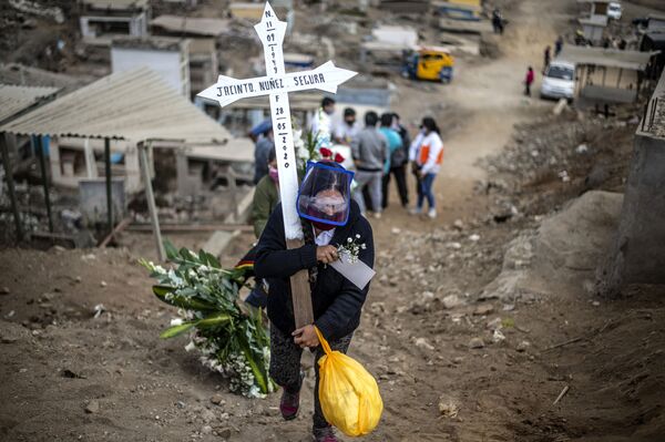 A relative of a suspected COVID-19 victim carries a cross during the burial at the Nueva Esperanza cemetery, one of the largest in Latin America, in the southern outskirts of Lima on May 30, 2020.  - Sputnik International