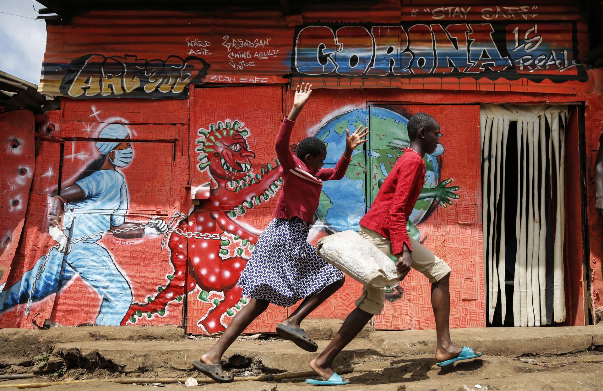 Children run down a street past an informational mural warning people about the dangers of the new coronavirus, in the Kibera slum, or informal settlement, of Nairobi, Kenya Wednesday, June 3, 2020.  - Sputnik International, 1920, 28.10.2022