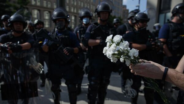 A demonstrator holds flowers as to place at the feet of a line of military near the White House to protest the death of George Floyd, Wednesday, June 3, 2020, in Washington - Sputnik International