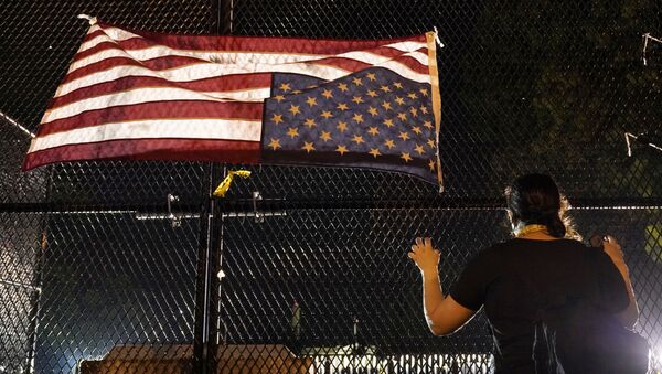 A demonstrator looks on next to an upside-down American flag at a fence in front of the White House, during a protest against the death in police custody of George Floyd, in Washington, U.S., June 4, 2020.  - Sputnik International