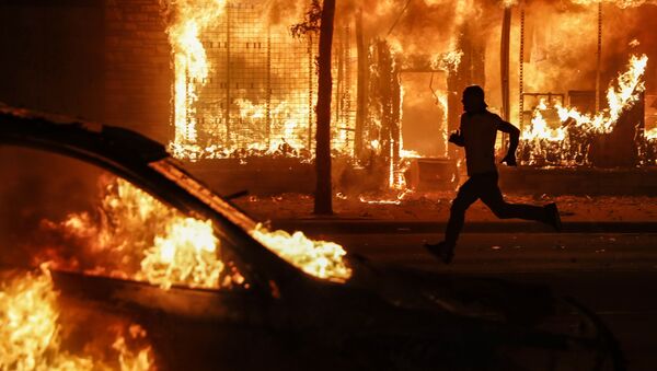 A protester runs past burning cars and buildings on Chicago Avenue, Saturday, May 30, 2020, in St. Paul, Minn. Protests continued following the death of George Floyd, who died after being restrained by Minneapolis police officers on Memorial Day. - Sputnik International