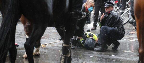 A colleague attends to a police officer who was injured when falling of a horse during scuffles with demonstrators at Downing Street during a Black Lives Matter march in London, Saturday, June 6, 2020, as people protest against the killing of George Floyd by police officers in Minneapolis, USA. - Sputnik International
