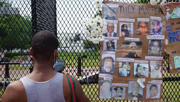 A man stands next to photos of victims of police brutality displayed on a metal fence during a protest near the White House in Washington DC, US, 06.06.2020. - Sputnik International
