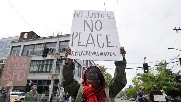 Demonstrator Kathy Woodward holds up a sign as she protests police actions, Thursday, June 4, 2020, in Seattle, following protests over the death of George Floyd, a black man who died after being restrained by Minneapolis police officers on May 25. - Sputnik International