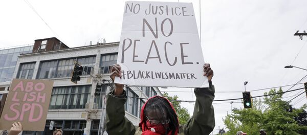 Demonstrator Kathy Woodward holds up a sign as she protests police actions, Thursday, June 4, 2020, in Seattle, following protests over the death of George Floyd, a black man who died after being restrained by Minneapolis police officers on May 25. - Sputnik International