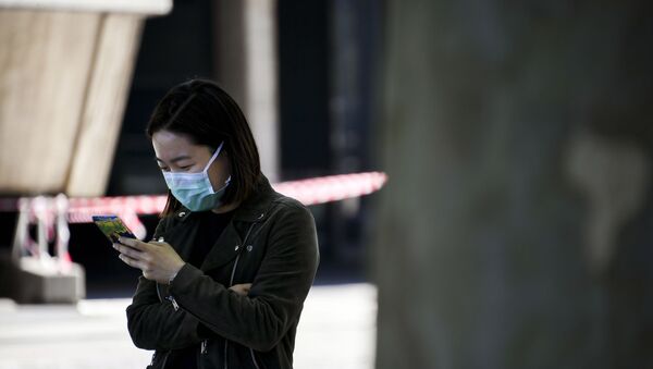 A woman wearing a face mask looks at her phone on the south bank of the river Thames, as the lockdown due to the coronavirus outbreak continues, in London, Saturday, April 25, 2020. - Sputnik International