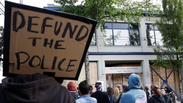 A protester holds a sing that reads defund the police after Seattle Police vacated the department's East Precinct and people continue to rally against racial inequality and the death in Minneapolis police custody of George Floyd, in Seattle, Washington, U.S. June 8, 2020. - Sputnik International