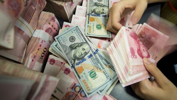 A Chinese bank employee counts 100-yuan notes and US dollar bills at a bank counter in Nantong in China's eastern Jiangsu province on August 28, 2019 - Sputnik International