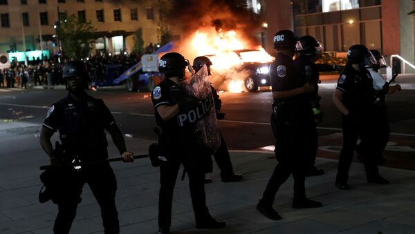 Police officers look on as a car burns in the back as protesters continue to rally against the death in Minneapolis police custody of George Floyd, near the White House, in Washington, U.S., May 30, 2020. - Sputnik International