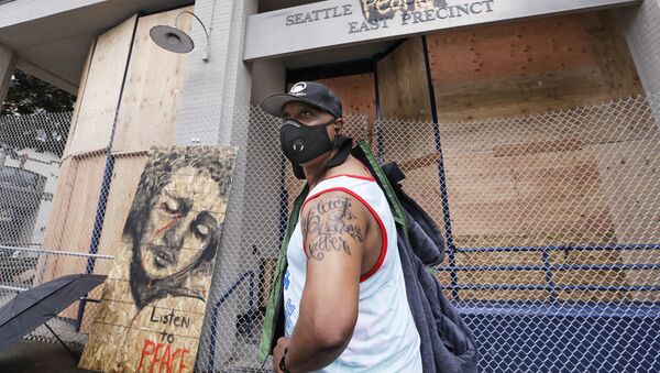 Rodney Maine displays his new Black Lives Matter tattoo after asking a passerby to take his photo in front of a plywood-covered and fenced-off Seattle police precinct Tuesday, June 9, 2020, in Seattle. - Sputnik International