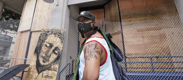 Rodney Maine displays his new Black Lives Matter tattoo after asking a passerby to take his photo in front of a plywood-covered and fenced-off Seattle police precinct Tuesday, June 9, 2020, in Seattle. - Sputnik International